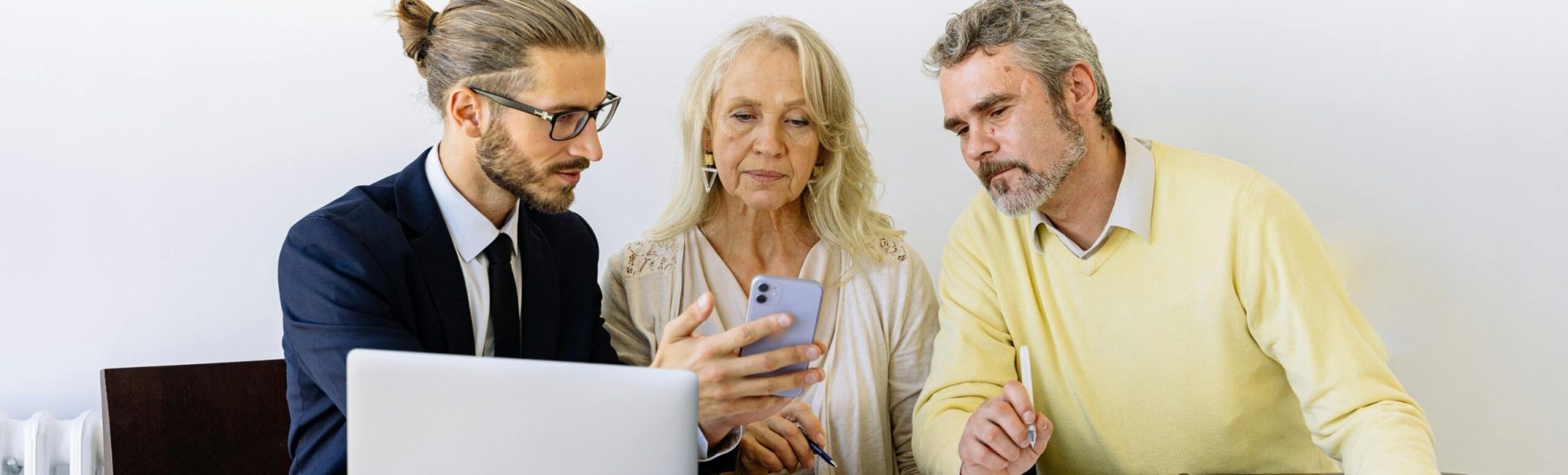 Three individuals collaborating on financial documents during a business meeting.